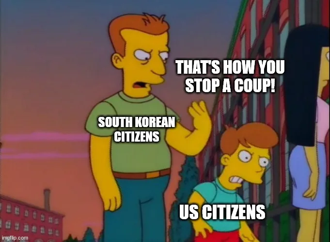 A still from The Simpsons shows a man in a green shirt gesturing with his hand while saying 'THAT'S HOW YOU STOP A COUP!'…