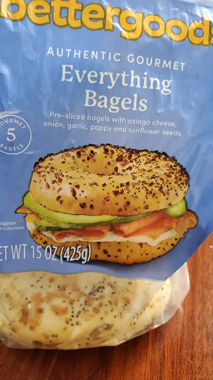 A close-up of a 'Bettergoods' brand bagel package showing 'Authentic Gourmet Everything Bagels' with text describing them as…