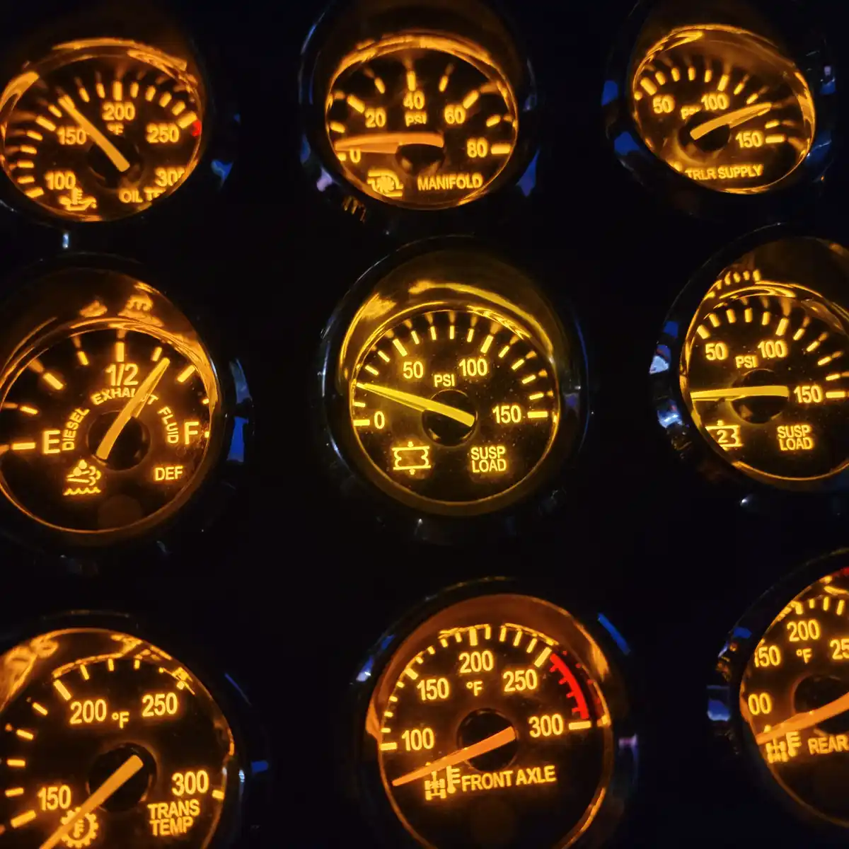 A close-up of a truck's illuminated dashboard with multiple glowing gauges showing oil temperature, manifold pressure…