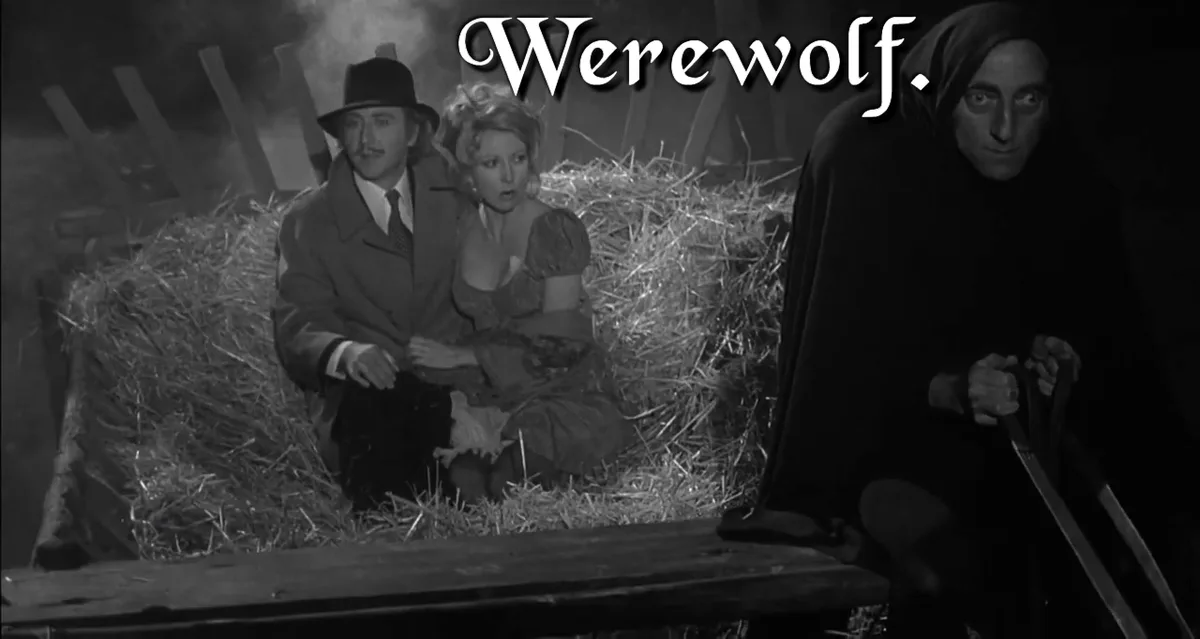 A black-and-white still from a classic horror film shows a man and woman crouched in hay, looking terrified, while a hooded…