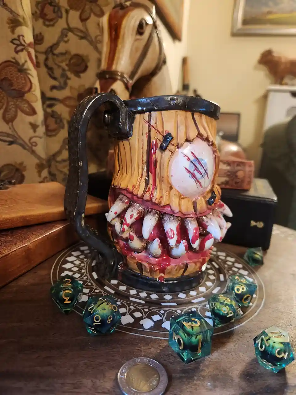 A grotesque, gory mug designed to look like a monster's head with a single eyeball, bloody teeth, and a black metal handle…