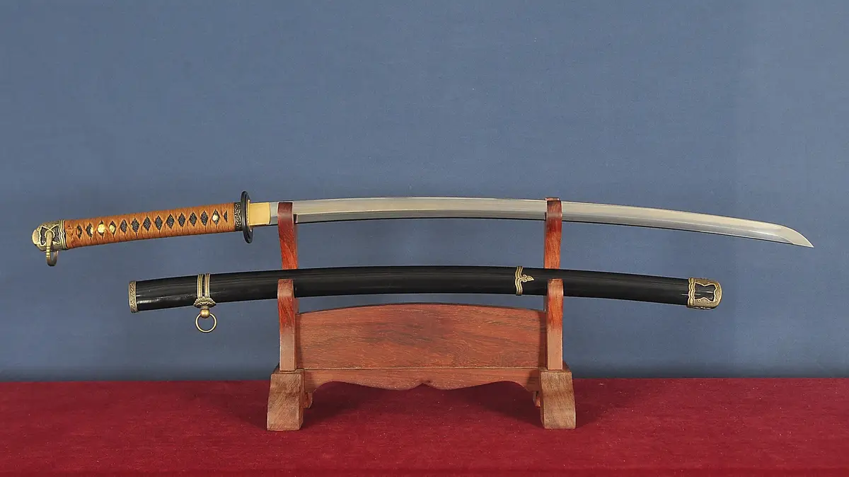 A traditional Japanese katana sword with a polished steel blade and ornate wooden handle is displayed horizontally on a…
