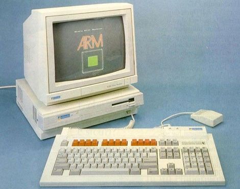 An old beige computer with a CRT monitor displaying the word 'ARM' and a green chip graphic, paired with a matching keyboard…