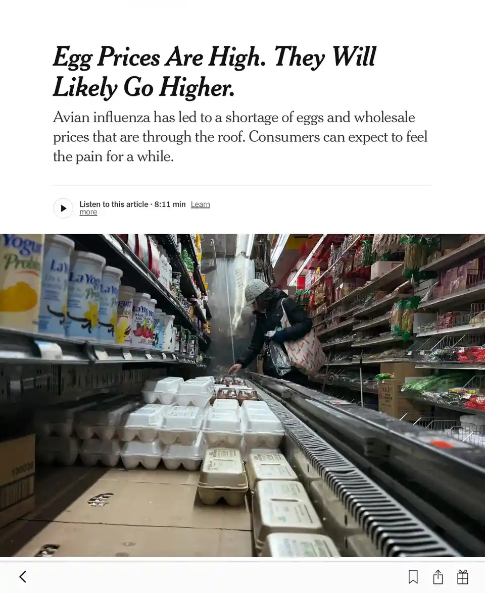 A person in a grocery store aisle is selecting eggs from a refrigerated shelf that is visibly sparse, with only a few…