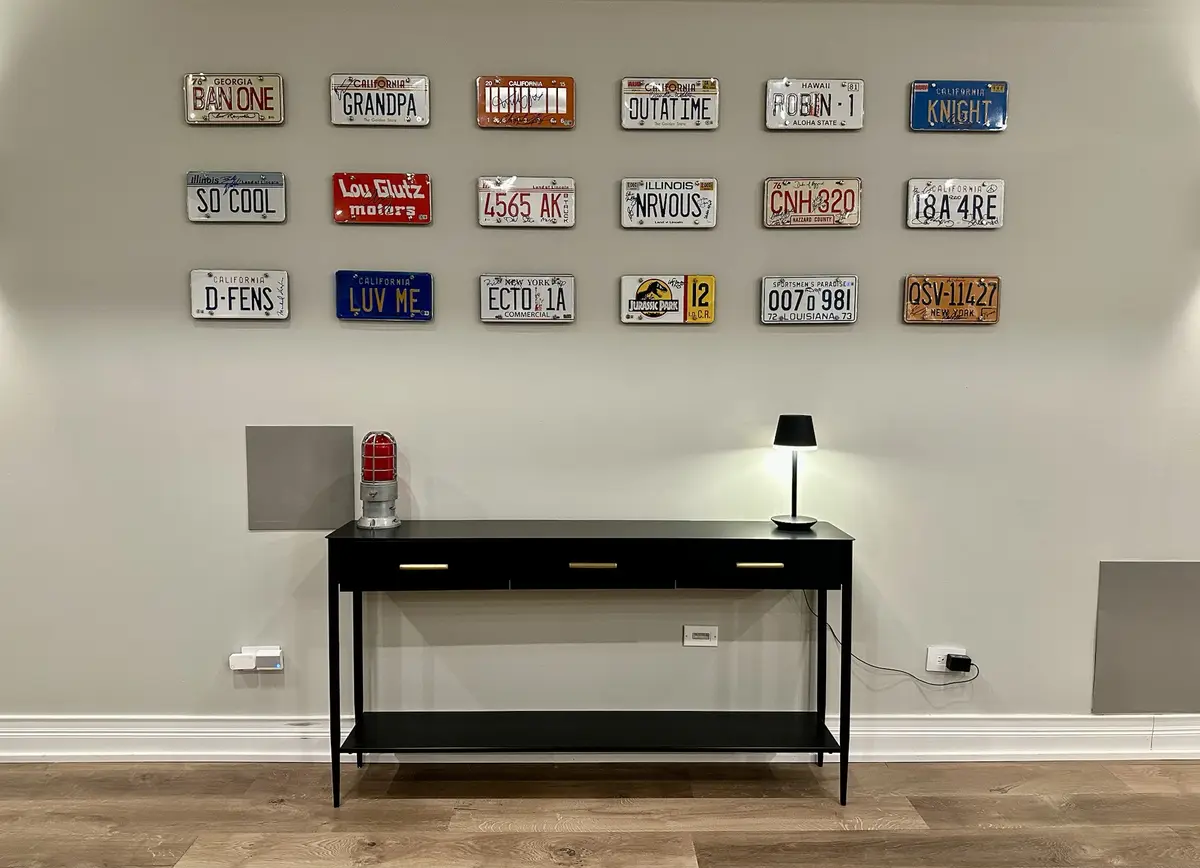 A wall displays a collection of decorative license plates from various U.S. states, including 'BAN ONE', 'GRANDPA'…