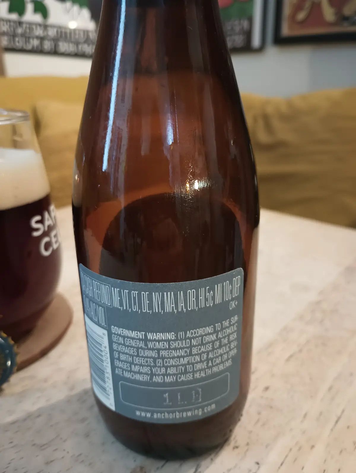 A close-up photo of the back label of a brown beer bottle, showing a standard government warning about alcohol consumption…