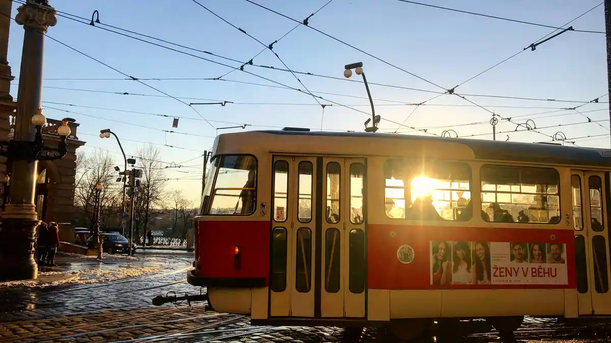 A rusty tram crawls across the canvas of a burning sky, where fiery hues of orange and pink dance across the clouds. Shadows…