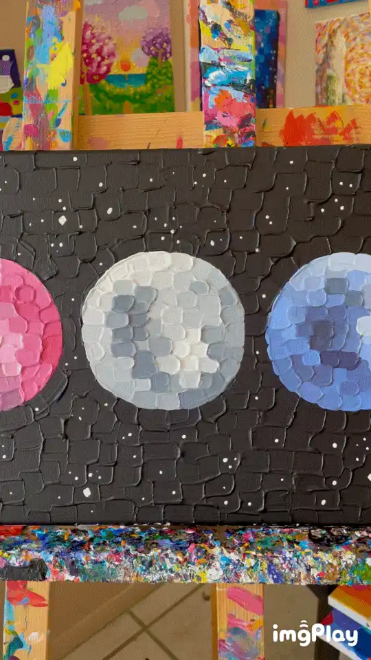 A series of three images show a painting on an easel depicting the moon phases, starting with a new moon, then waxing…