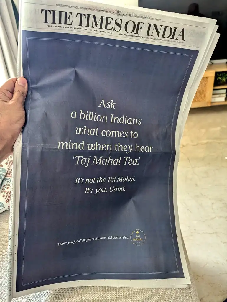 A hand holds a newspaper, The Times of India, displaying an advertisement that reads: 'Ask a billion Indians what comes to…