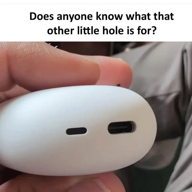 A close-up photo shows a person's hand holding a white, oval-shaped charging case, likely for wireless earbuds. Two small…