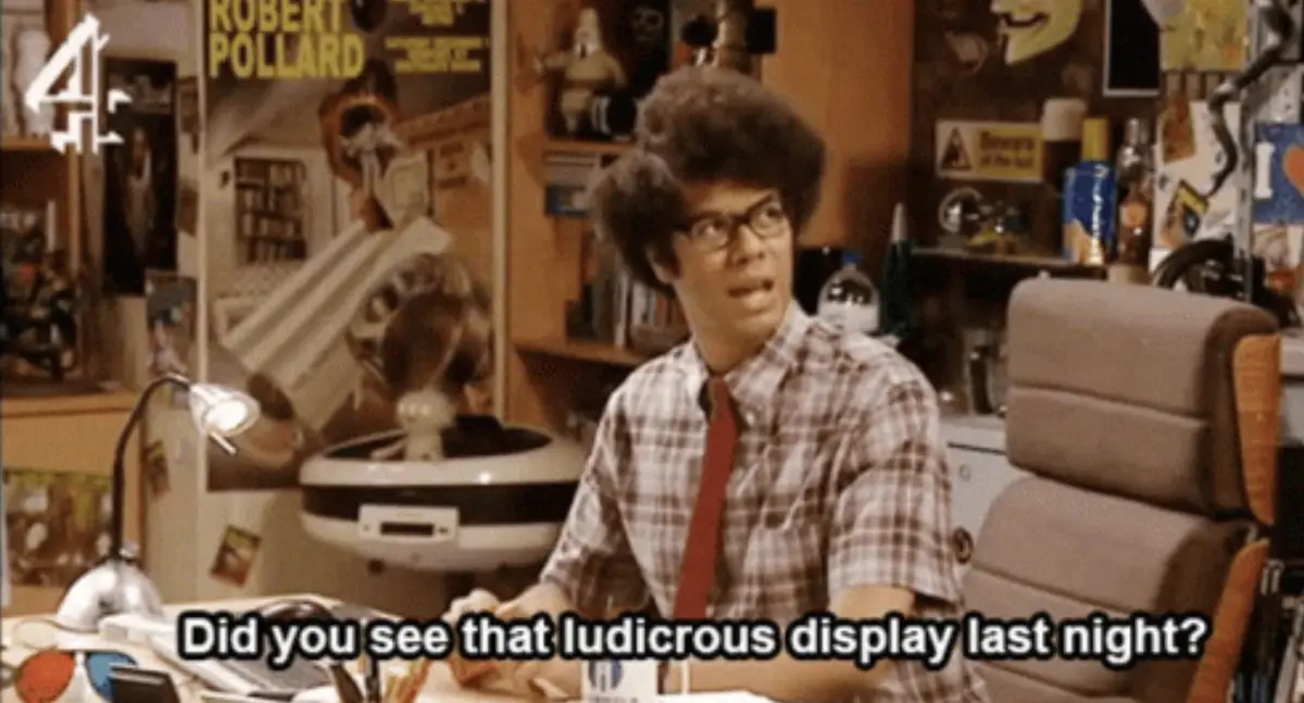 A man with an afro and glasses sits at a cluttered desk in a messy room, looking surprised. The text overlay reads 'Did you…