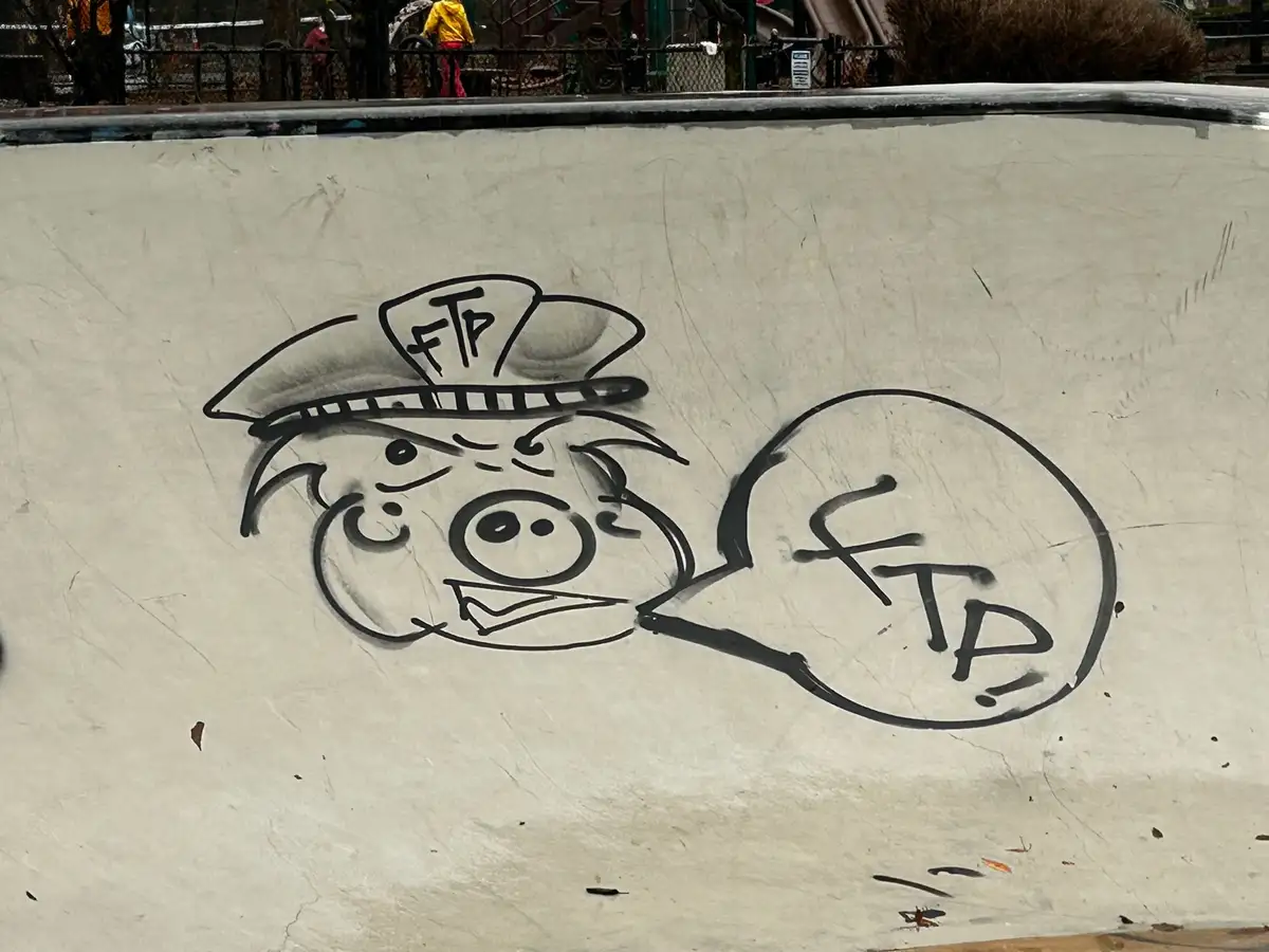 A black-and-white graffiti drawing on a concrete surface shows a cartoon pig wearing a hat with 'FTP' written on it…