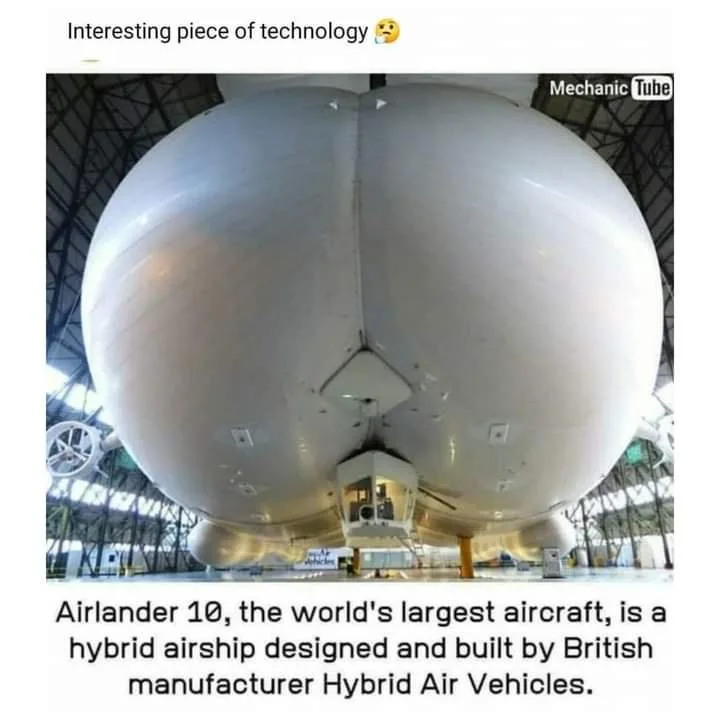 A close-up photo shows the massive, rounded, white underside of the Airlander 10 airship inside a hangar, with its gondola…