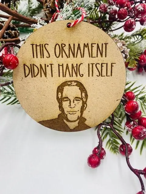 A circular wooden Christmas ornament with a laser-etched portrait of a smiling man and the text 'THIS ORNAMENT DIDN'T HANG…