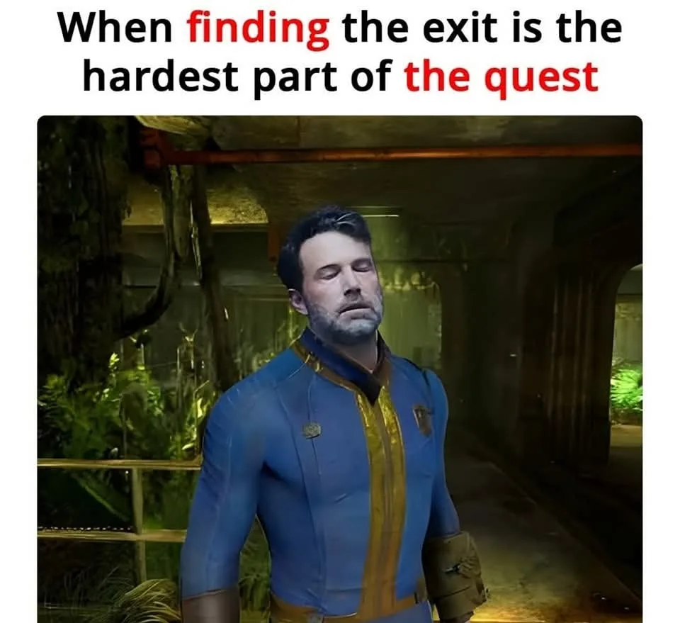 A man with a weary, resigned expression stands in a dim, overgrown corridor. He wears a blue and gold jumpsuit with a patch…