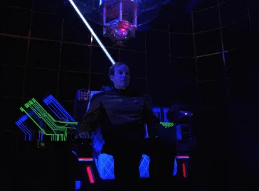A six-panel image sequence shows a man in a dark sci-fi uniform seated in a futuristic chair with glowing blue and green…