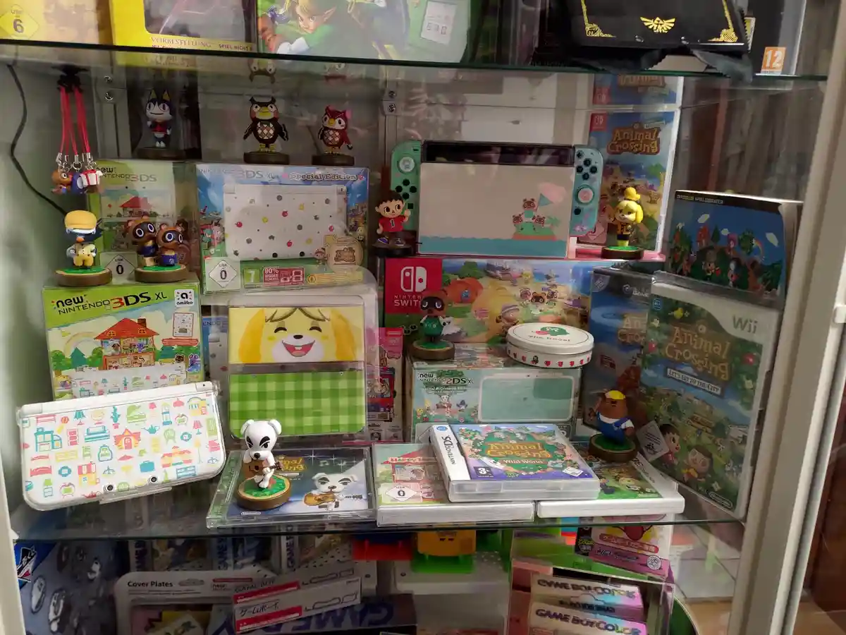 A glass display case is filled with Nintendo gaming merchandise, including multiple Animal Crossing-themed consoles, games…