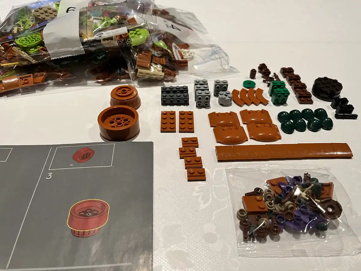 A close-up photo shows a LEGO set's instruction manual page labeled '3' with an illustration of a red wheel, next to a pile…
