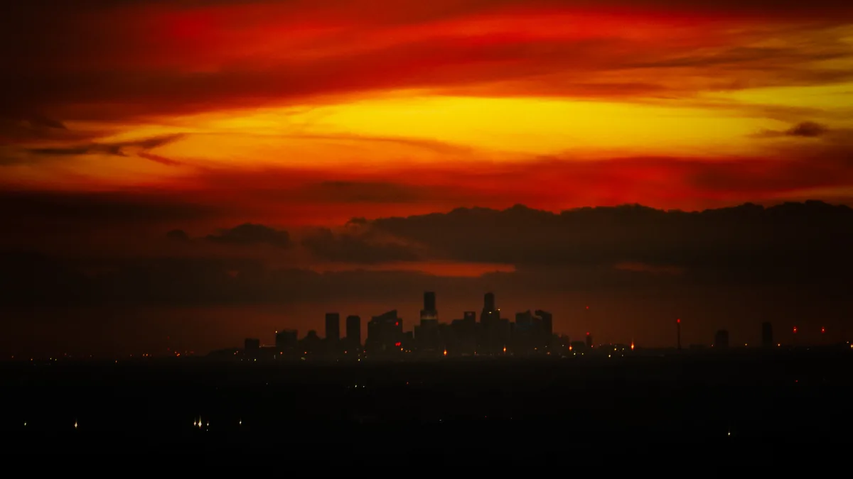 A dramatic sunset with fiery orange and red clouds above a dark city skyline, where the overlaid text reads 'i'm not crying…