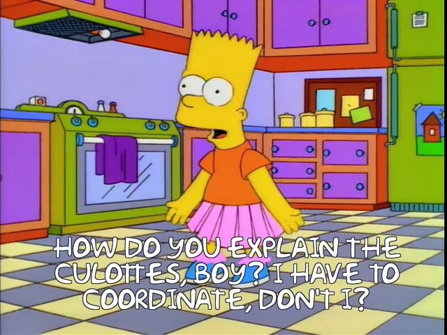 A still from The Simpsons shows Bart Simpson standing in a kitchen wearing a pink skirt and orange shirt, looking surprised…