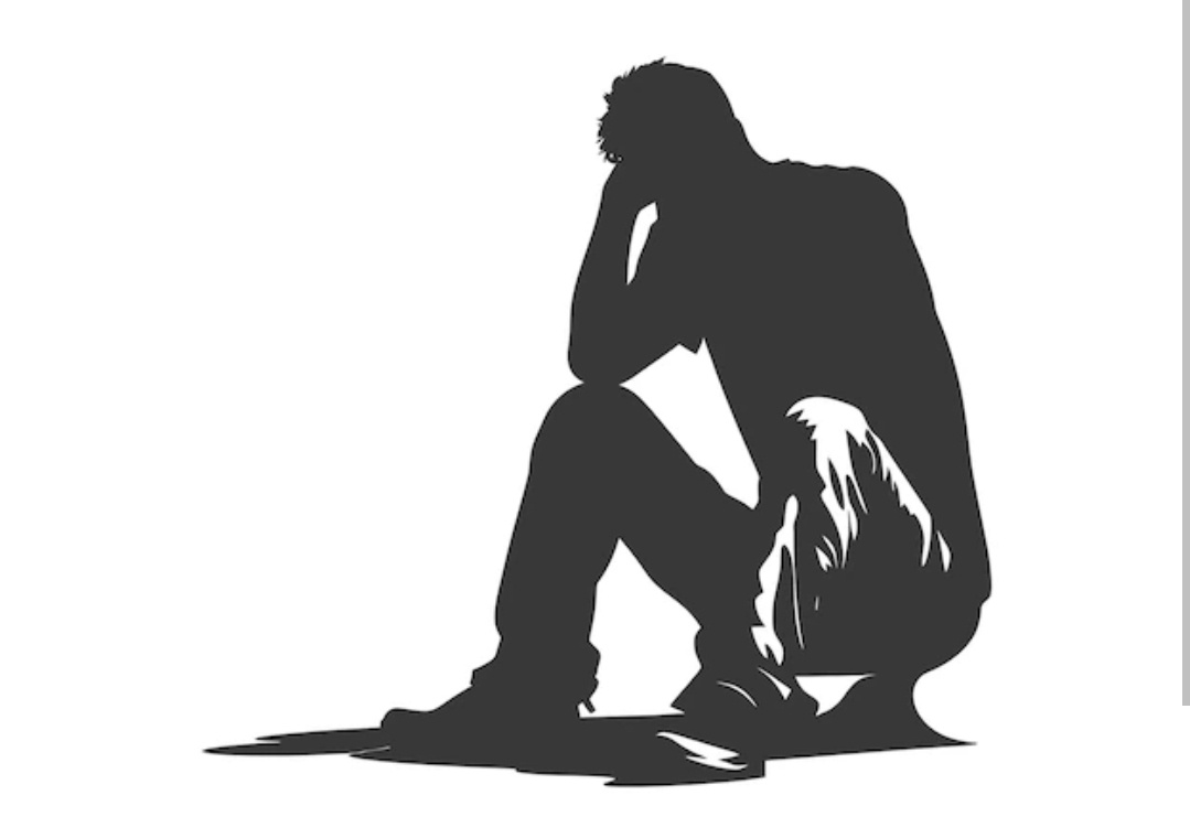 A black silhouette of a person sitting on the floor with their head in their hands, conveying sadness or despair. The image…