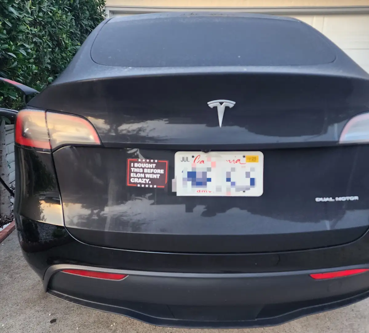 The rear view of a black Tesla Model 3 with a California license plate partially obscured by pixelation. A red-bordered…