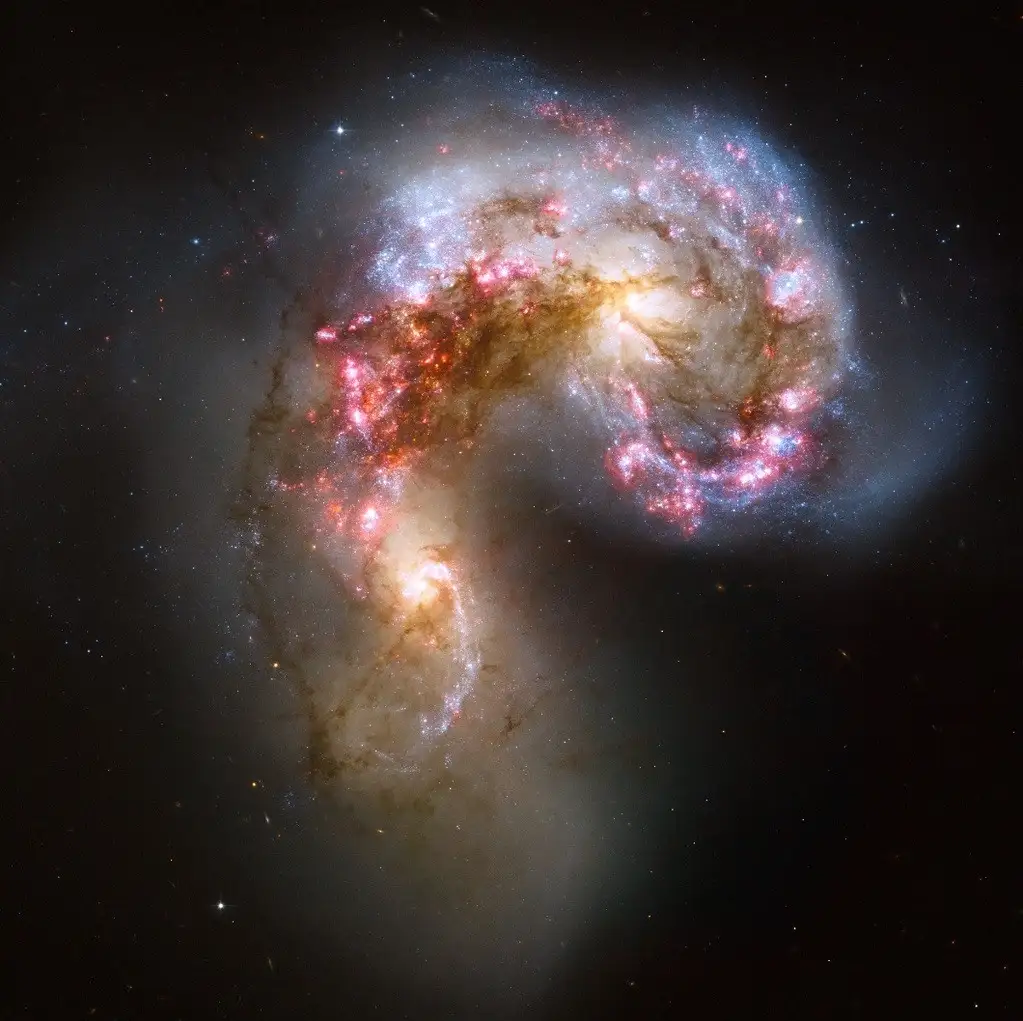 a cosmic image shows two galaxies colliding and merging, forming a shape that visually resembles a question mark, with…