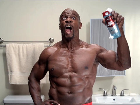 A muscular Black man with a shocked, yelling expression stands shirtless in a bathroom, holding up a can of shaving cream…