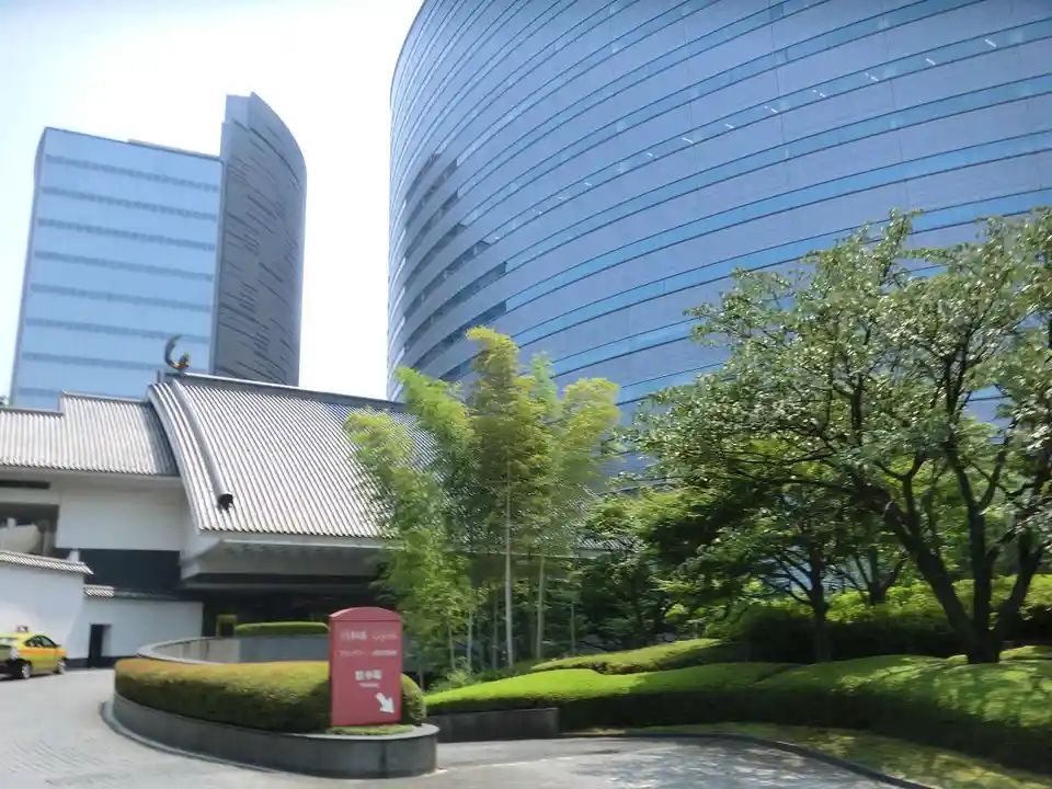 A photo of a modern glass skyscraper juxtaposed with a traditional Japanese-style building featuring a curved roof and…