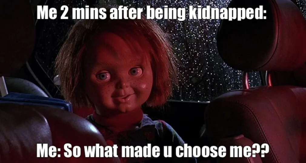 A still image from the movie Child's Play shows the doll Chucky sitting in a car seat, looking at the camera with a…