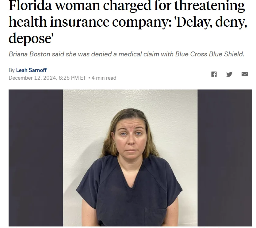 A mugshot-style photo shows a woman with a neutral expression wearing a dark blue V-neck shirt against a plain wall. The…