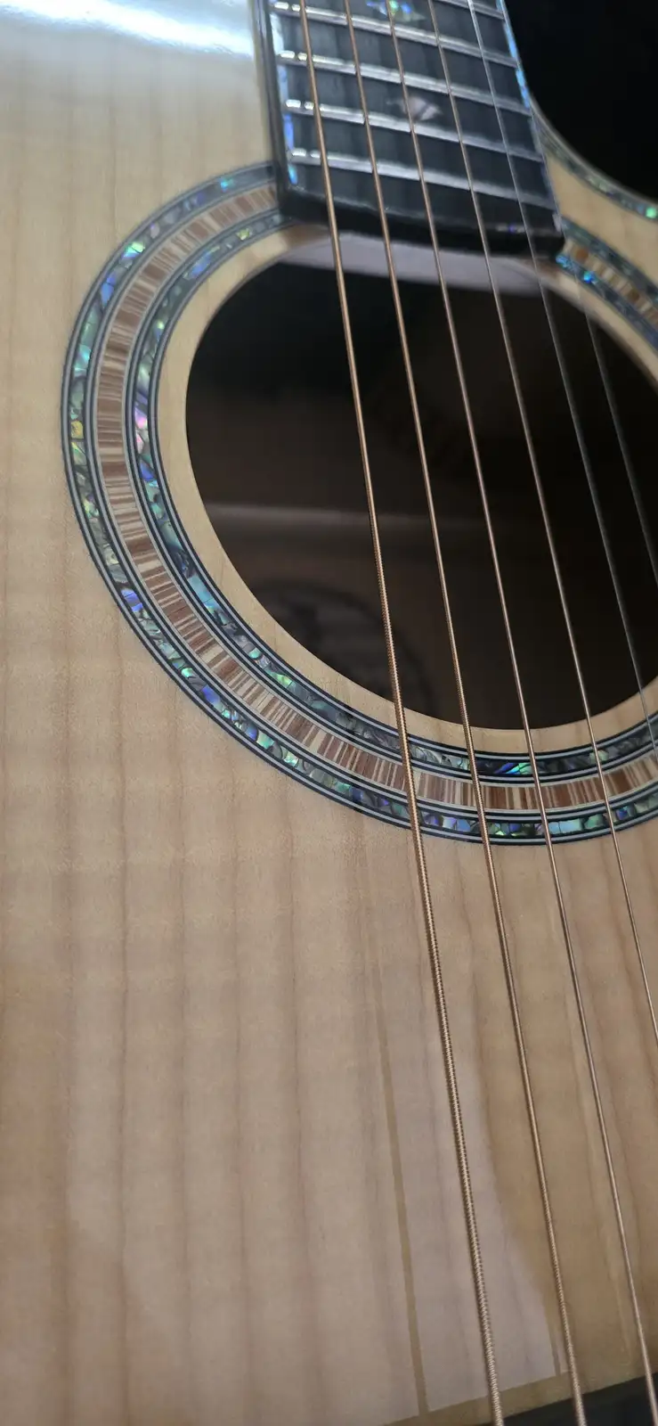 A close-up photo of an acoustic guitar's soundhole, showing the wooden body, strings, and decorative inlay. The overlaid…