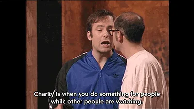 A meme image showing two men in a staged setting, with the man in the blue jacket repeating the phrase 'Charity is when you…