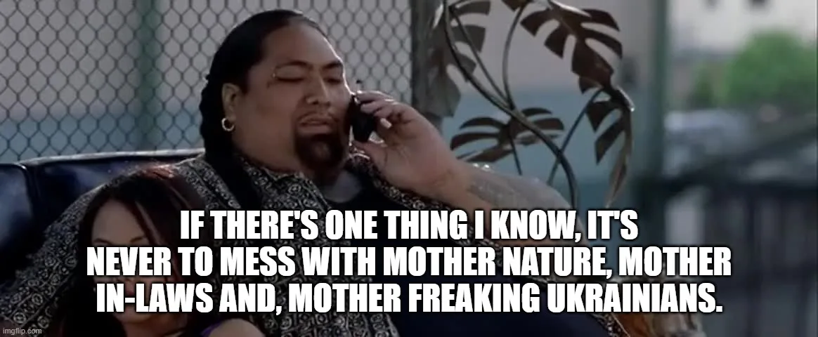 A man with long braids and a goatee is on the phone, looking serious, while a woman sits beside him. The overlaid text…