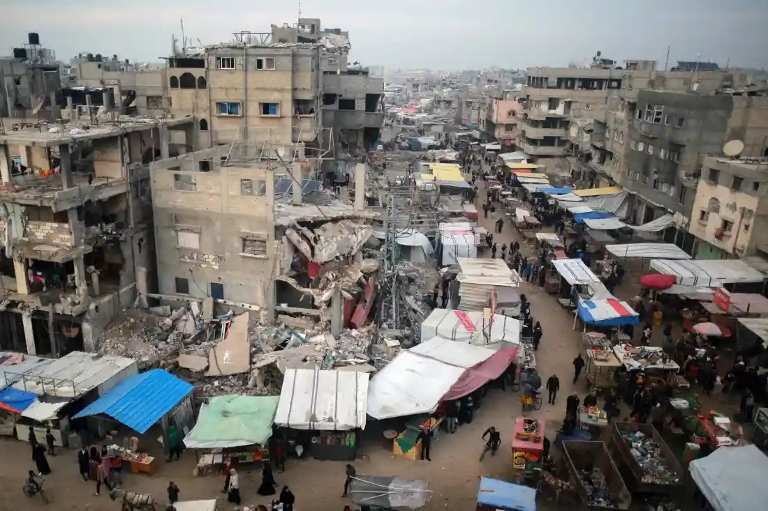 An aerial view of a densely populated urban area with heavily damaged and partially collapsed buildings on the left, while…