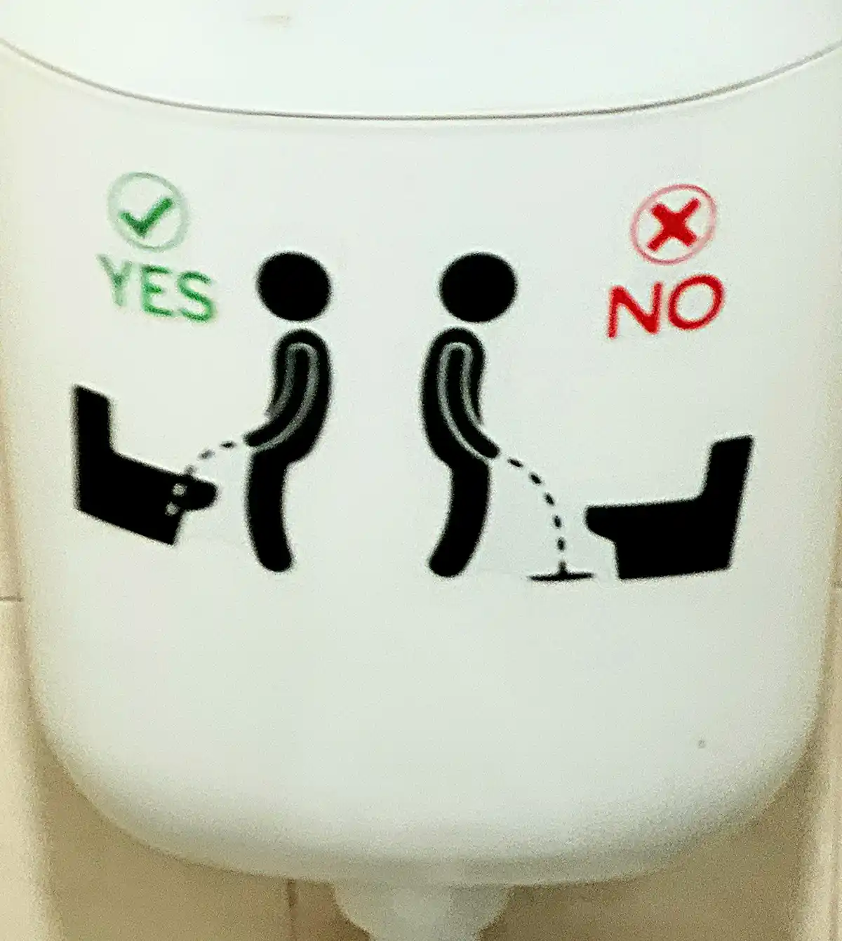 A close-up of a white toilet tank with a public restroom sign showing two stick figures. The figure on the left, labeled…