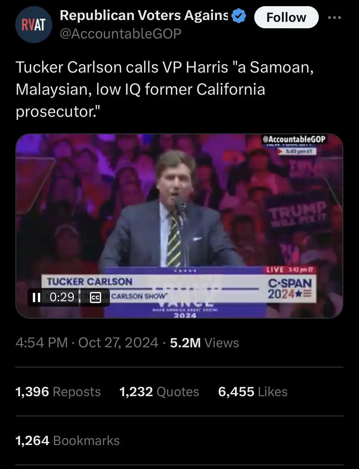 A screenshot from a C-SPAN broadcast shows Tucker Carlson speaking at a podium during a live show, with an audience visible…