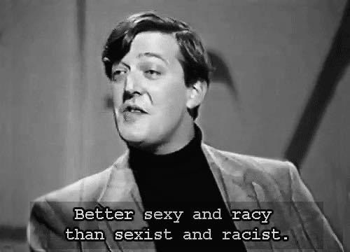 A black-and-white still of a man in a turtleneck and blazer, looking upward and to his right with a slightly smug or…