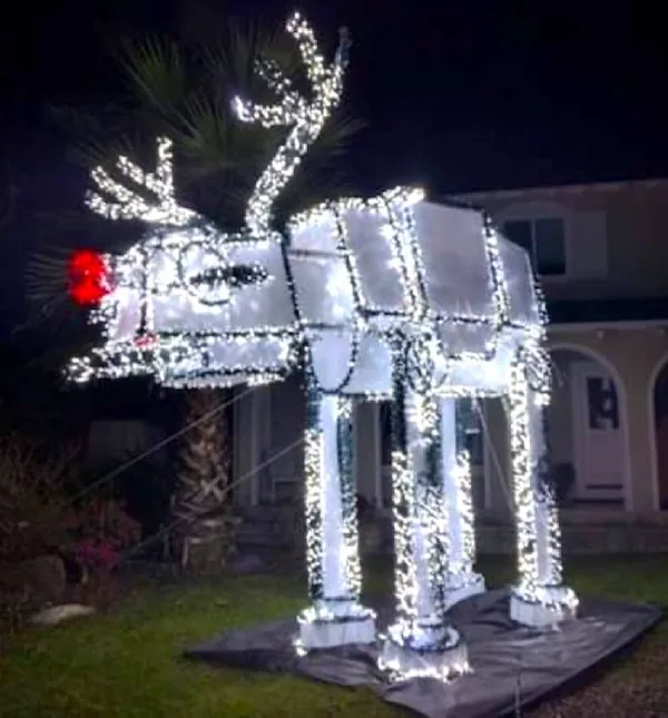 A large outdoor Christmas decoration shaped like a reindeer, constructed from white string lights, stands on a lawn at…