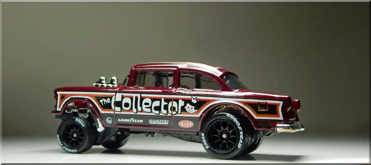 A maroon Hot Wheels-style die-cast model of a classic hot rod pickup truck is shown in profile against a plain gray…