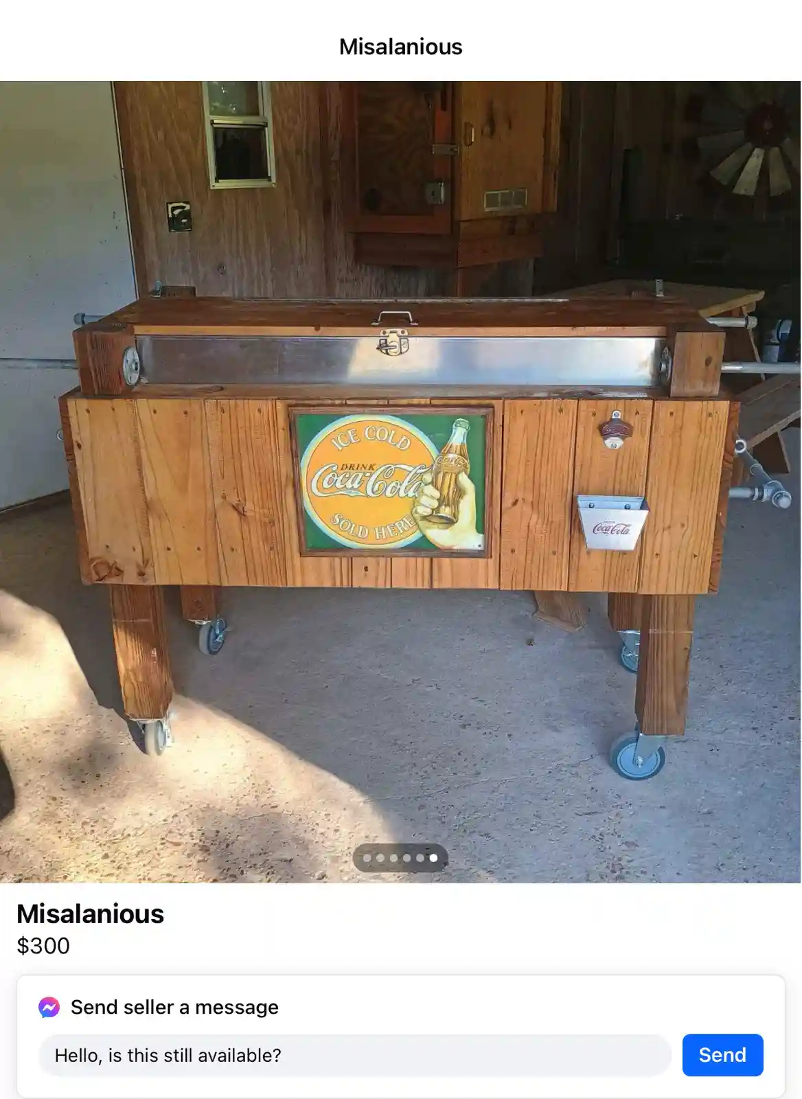 A wooden, wheeled Coca-Cola cooler with a vintage 'ICE COLD DRINK Coca-Cola SOLD HERE' sign and a bottle opener, displayed…