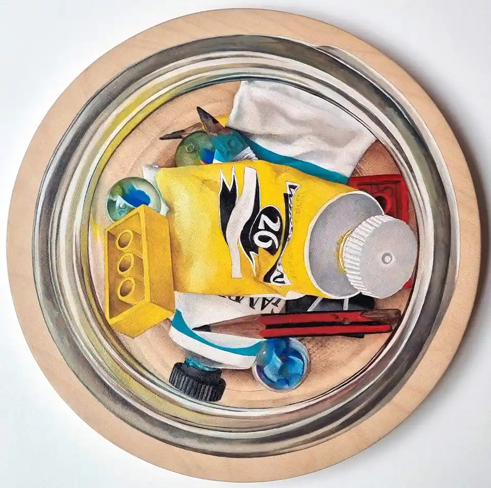 A circular painting depicts a cluttered collection of art supplies inside a jar, including a yellow paint tube with a black…