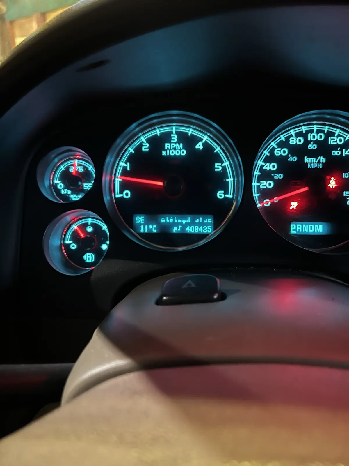 A close-up of a car's illuminated dashboard showing the speedometer, tachometer, and fuel gauge, with the digital display…