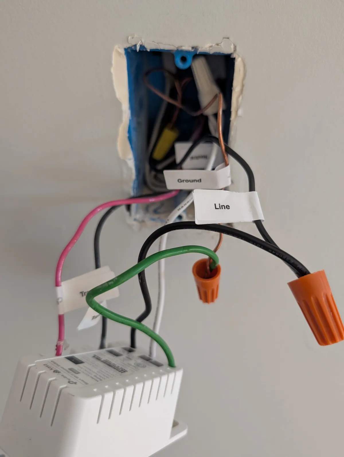 A close-up photo shows exposed electrical wiring in a wall box, with wires labeled 'Ground' and 'Line' using white tape…