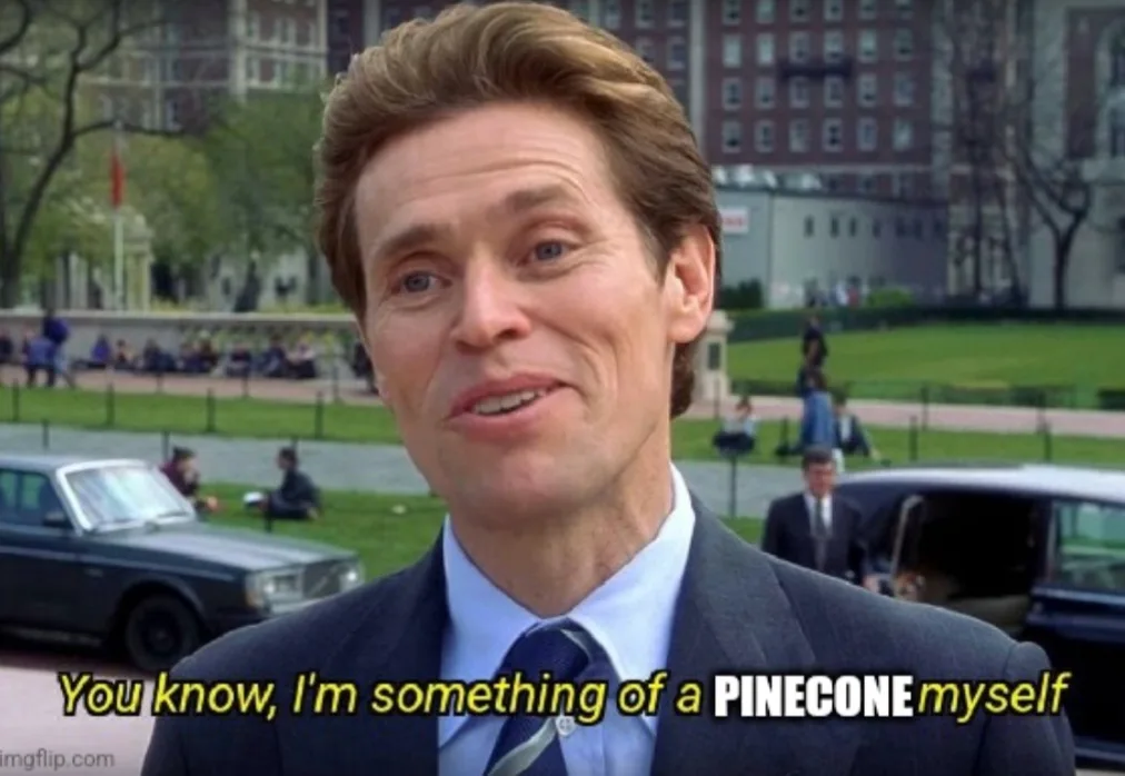 A man in a suit and tie smiles while speaking outdoors, with cars and buildings in the background. The overlaid text reads…