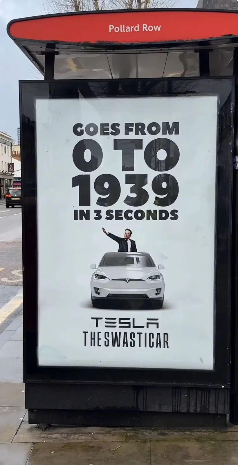 A bus stop advertisement for Tesla features a white Tesla car with Elon Musk waving from the roof. The ad claims the car…