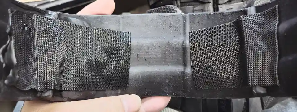 A close-up photo shows a person holding a black, textured insole or sole piece from a shoe, which has a visible hole in the…