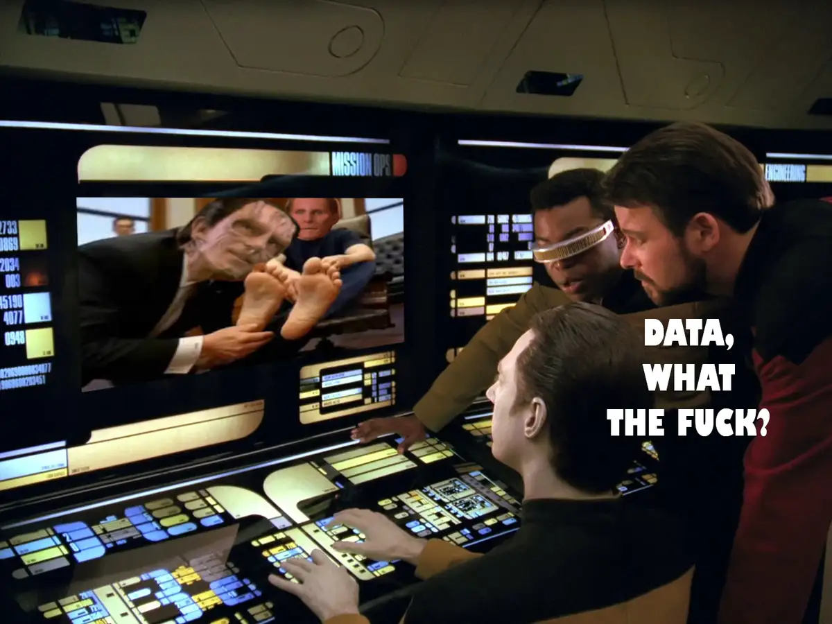In a Star Trek bridge scene, crew members look at a screen showing a man in a suit staring at another man's bare feet. White…