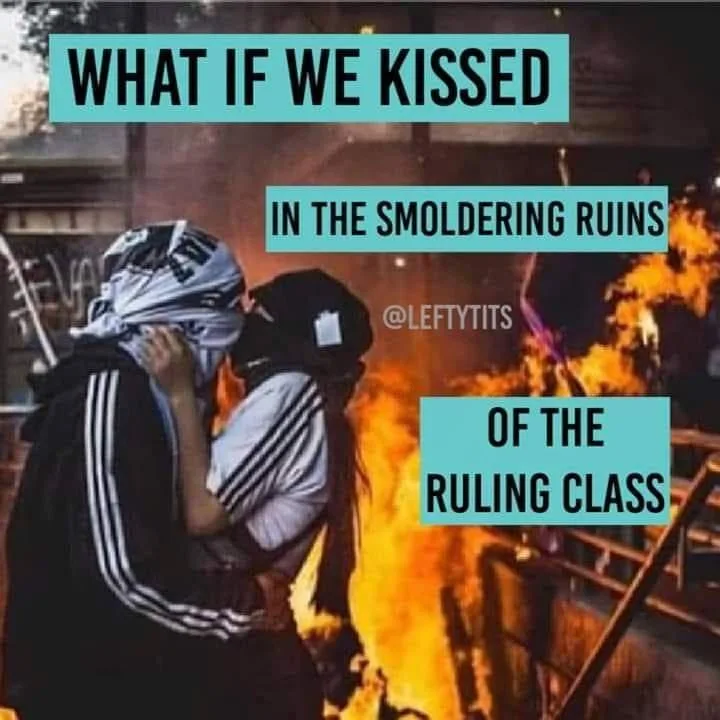 Two people wearing black and white athletic jackets and face coverings are kissing in front of a large fire. The image has…