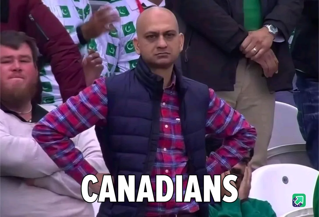 A bald man in a red plaid shirt and black vest stands with hands on hips in a stadium, looking intensely at the camera…